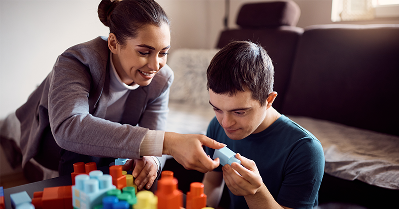 teacher handing special education student a block