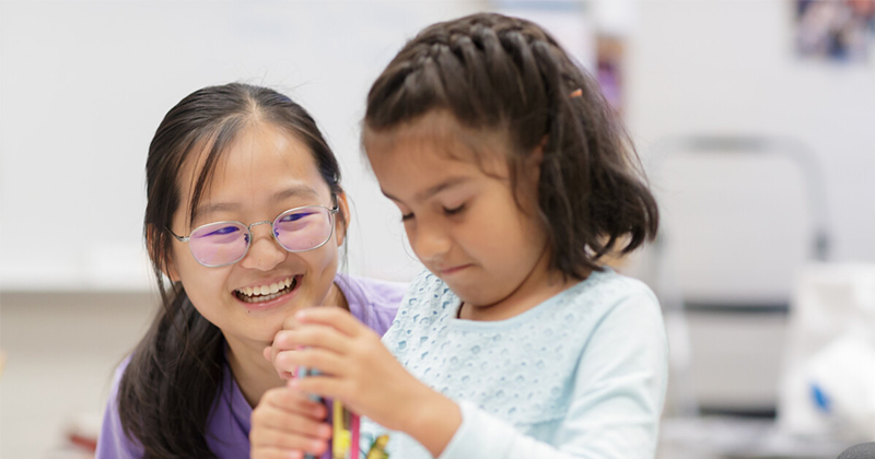 special education teacher sitting beside student