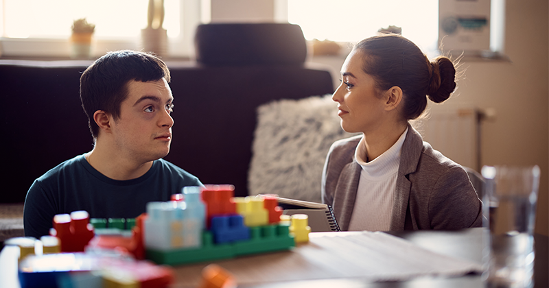 special education teacher at table with teen student