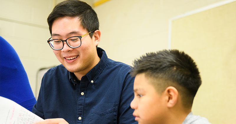 teacher in blue shirt at desk with student