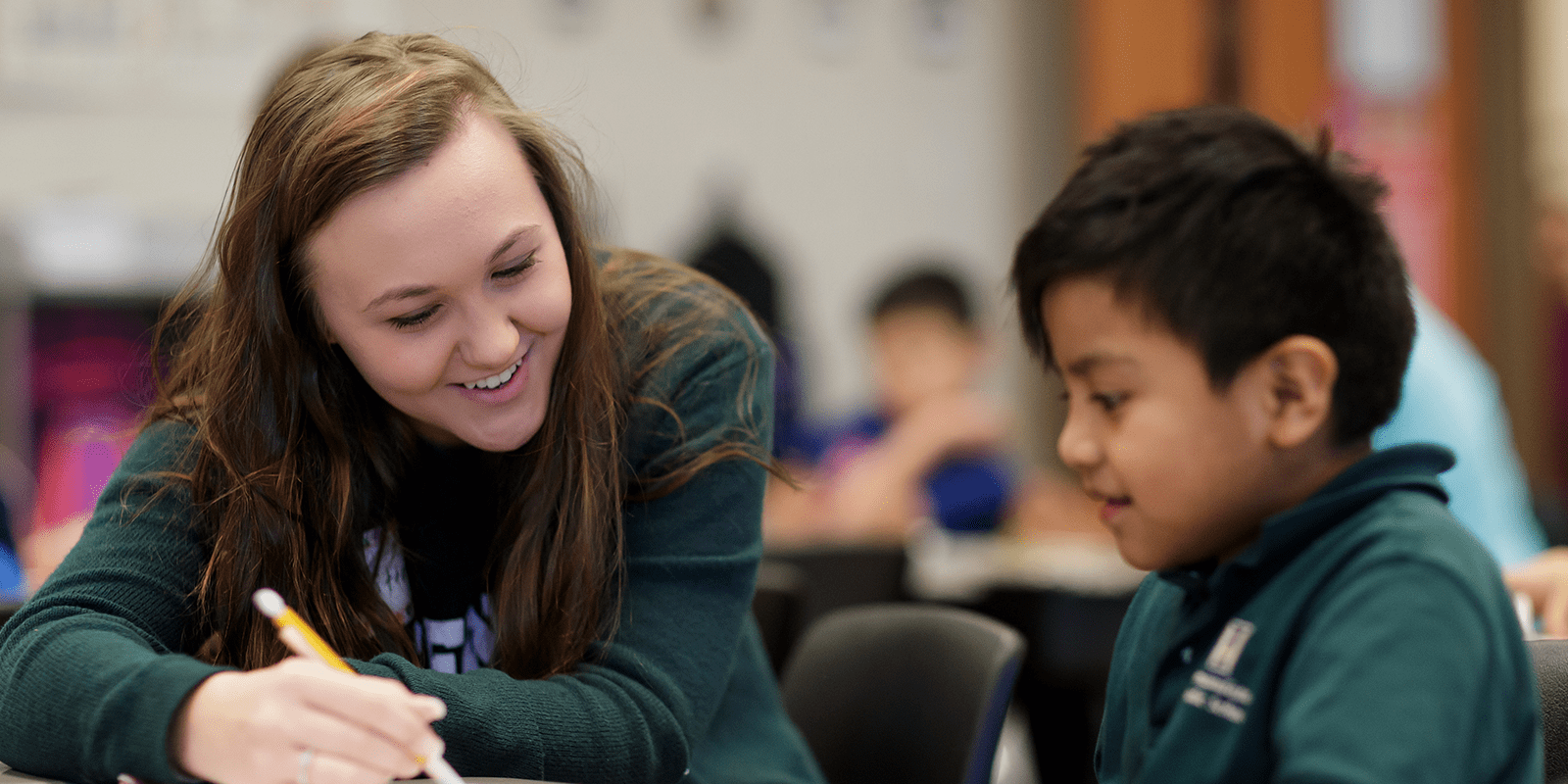 teacher in green shirt teaching English as second language to young student
