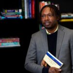 Middle school educator holds "Teaching Them to Read" book in office library
