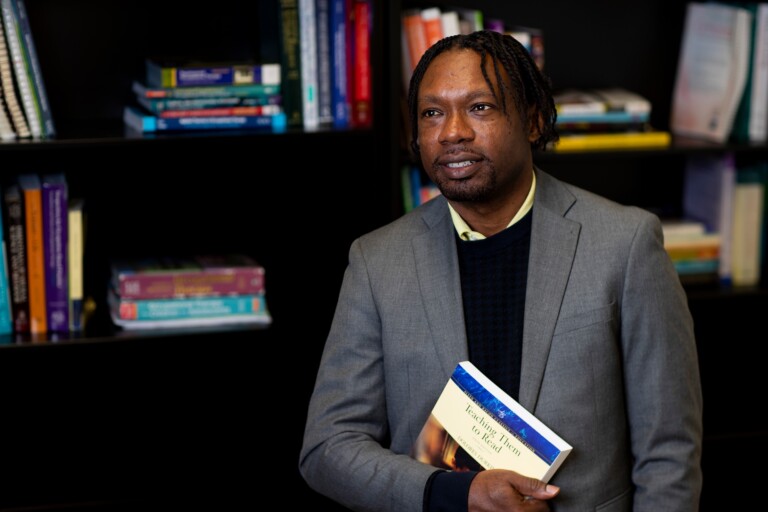 Middle school educator holds "Teaching Them to Read" book in office library